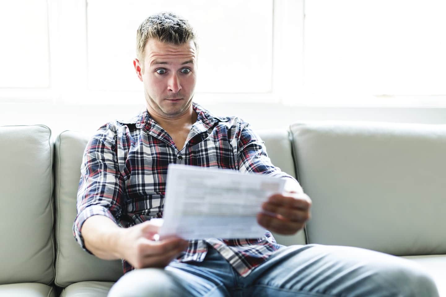 Shocked man holding some documents on sofa livingroom