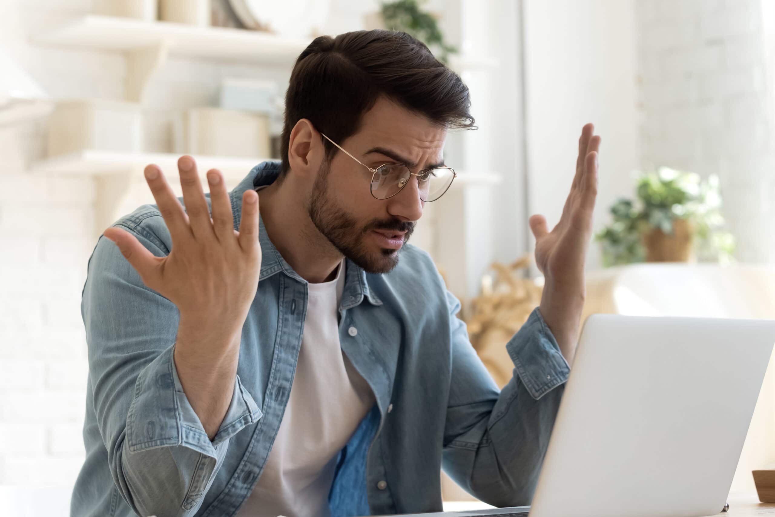 Angry frustrated young man furious about laptop computer malfunction