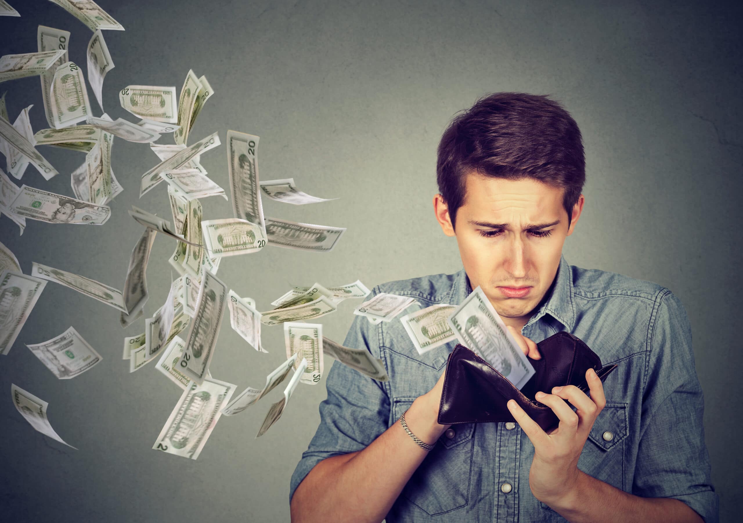 Sad man looking at wallet with money dollars flying away