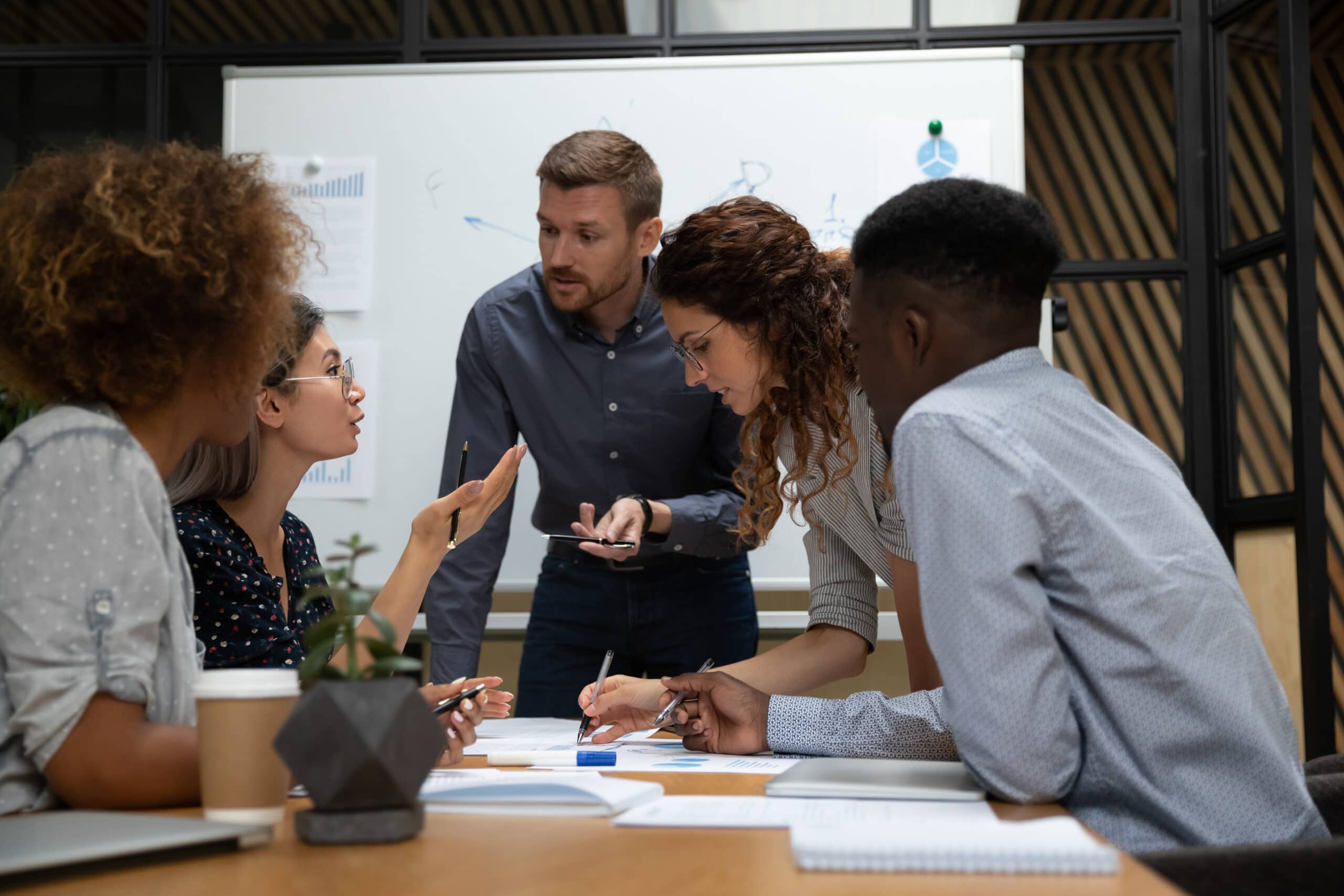 Busy millennial group of motivated mixed race teammates discussing project.