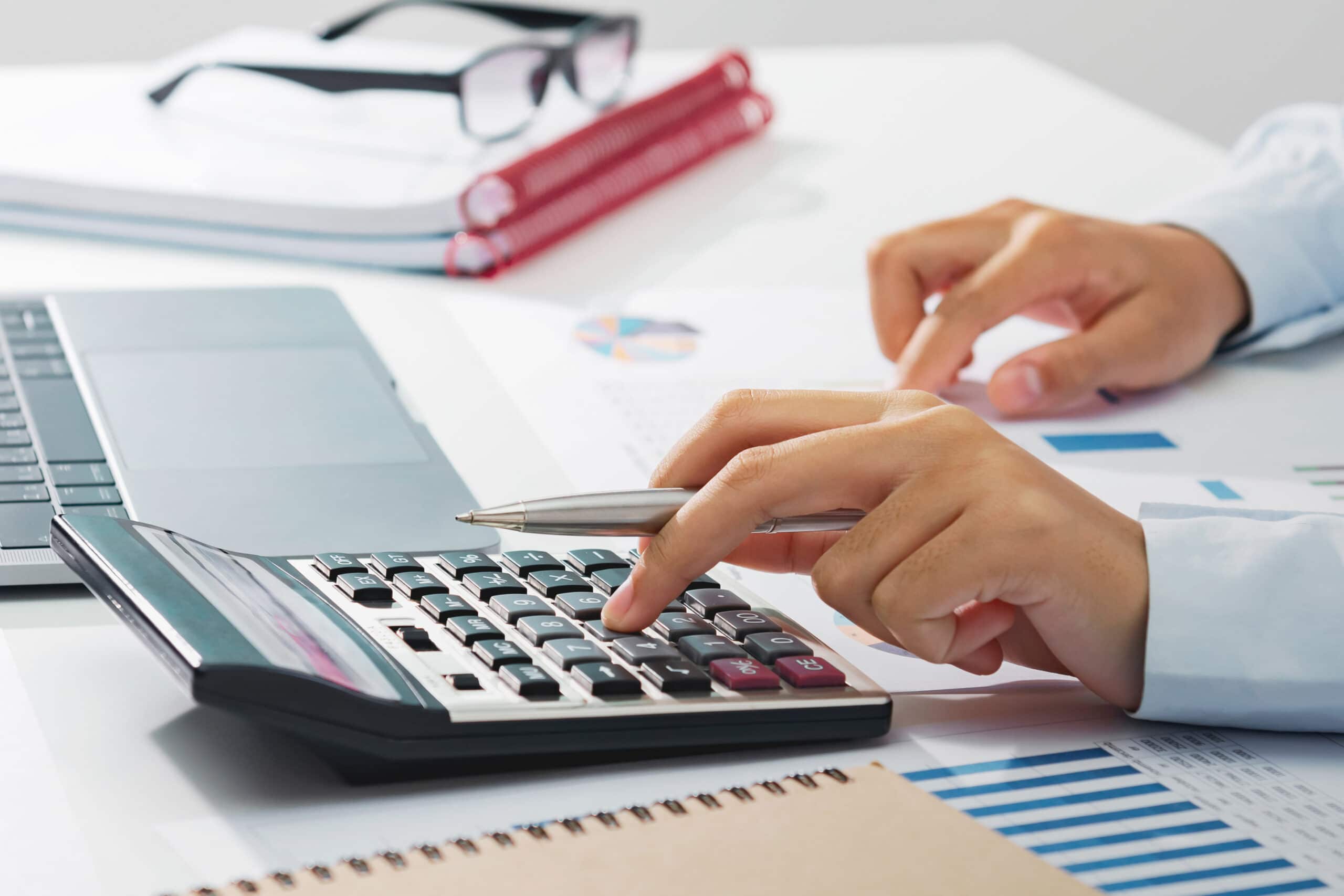 businesswoman working on desk using calculator analyzing finance